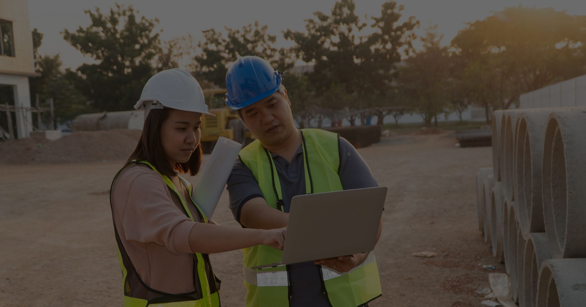 Construction workers on job site entering information on a laptop