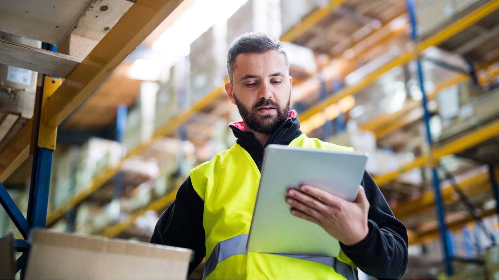 man in warehouse looking at tablet